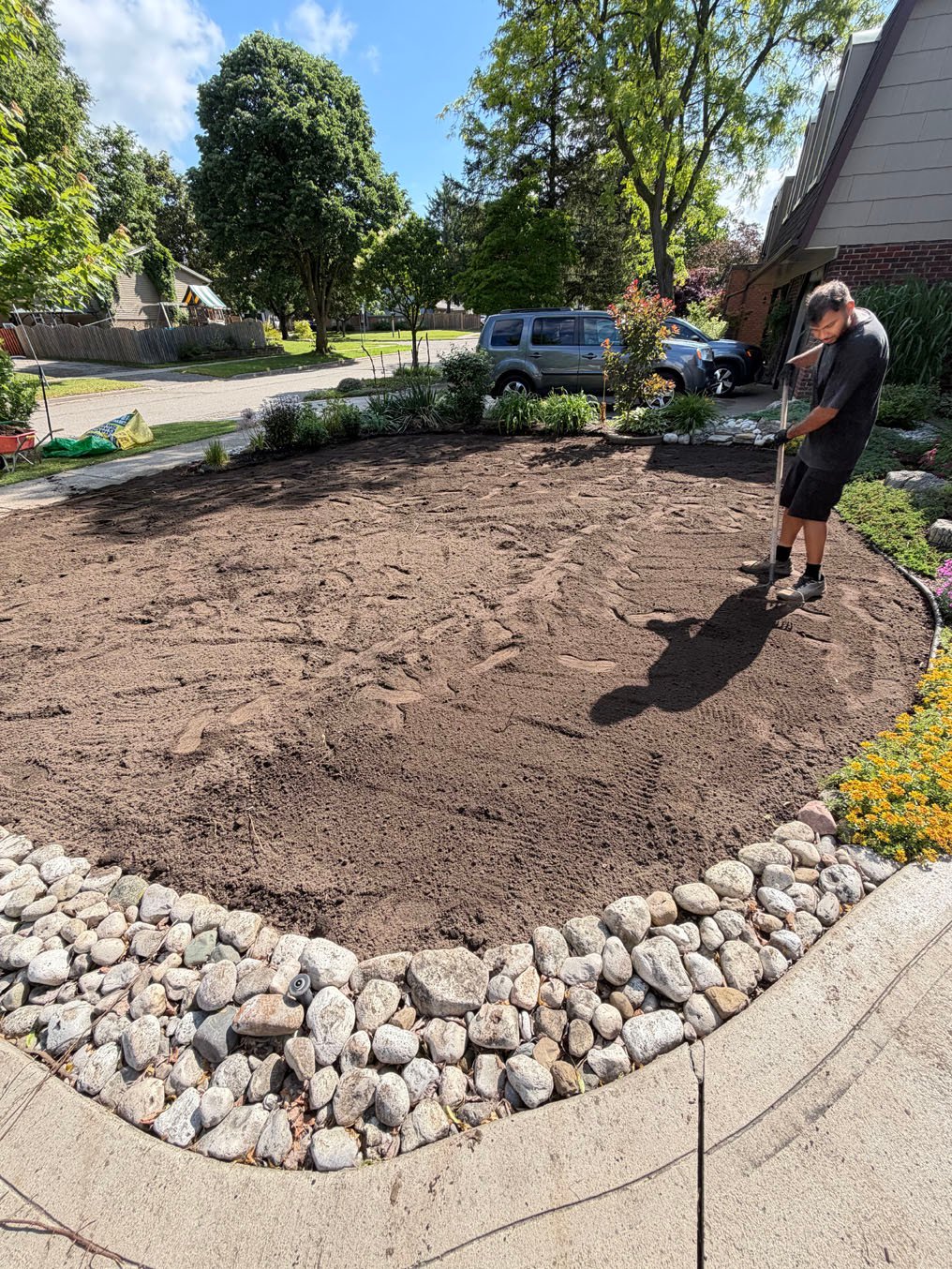 Fresh topsoil being spread over the stripped corner lawn in Centreville Chicopee, Kitchener