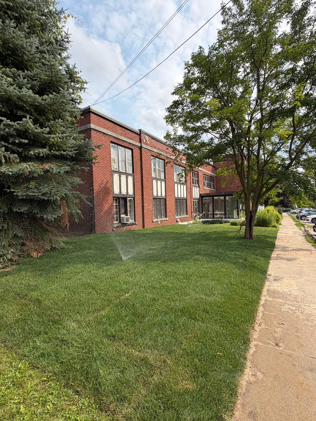 Sprinkler running on the new sod lawn beside the brick building in Cherry Hill, Kitchener