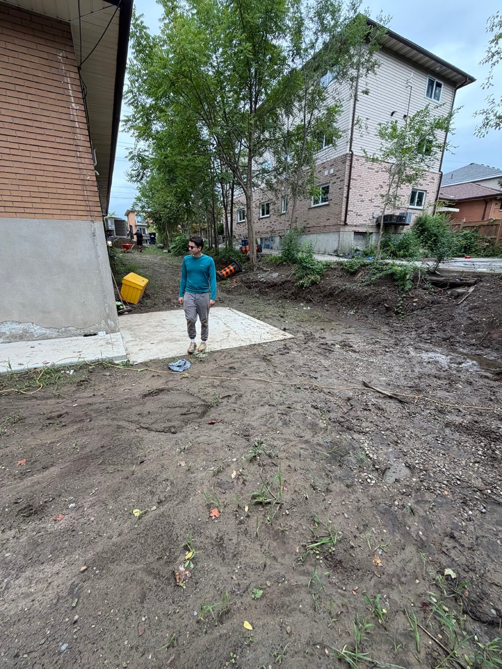 Crew on the cleared, rough-graded side yard of a brick building on Columbia Street West, Waterloo