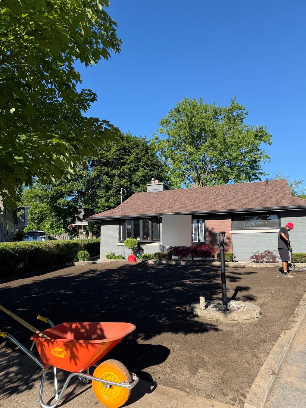 Fresh topsoil spread across the front lawn with a wheelbarrow at the Fairfield, Kitchener job