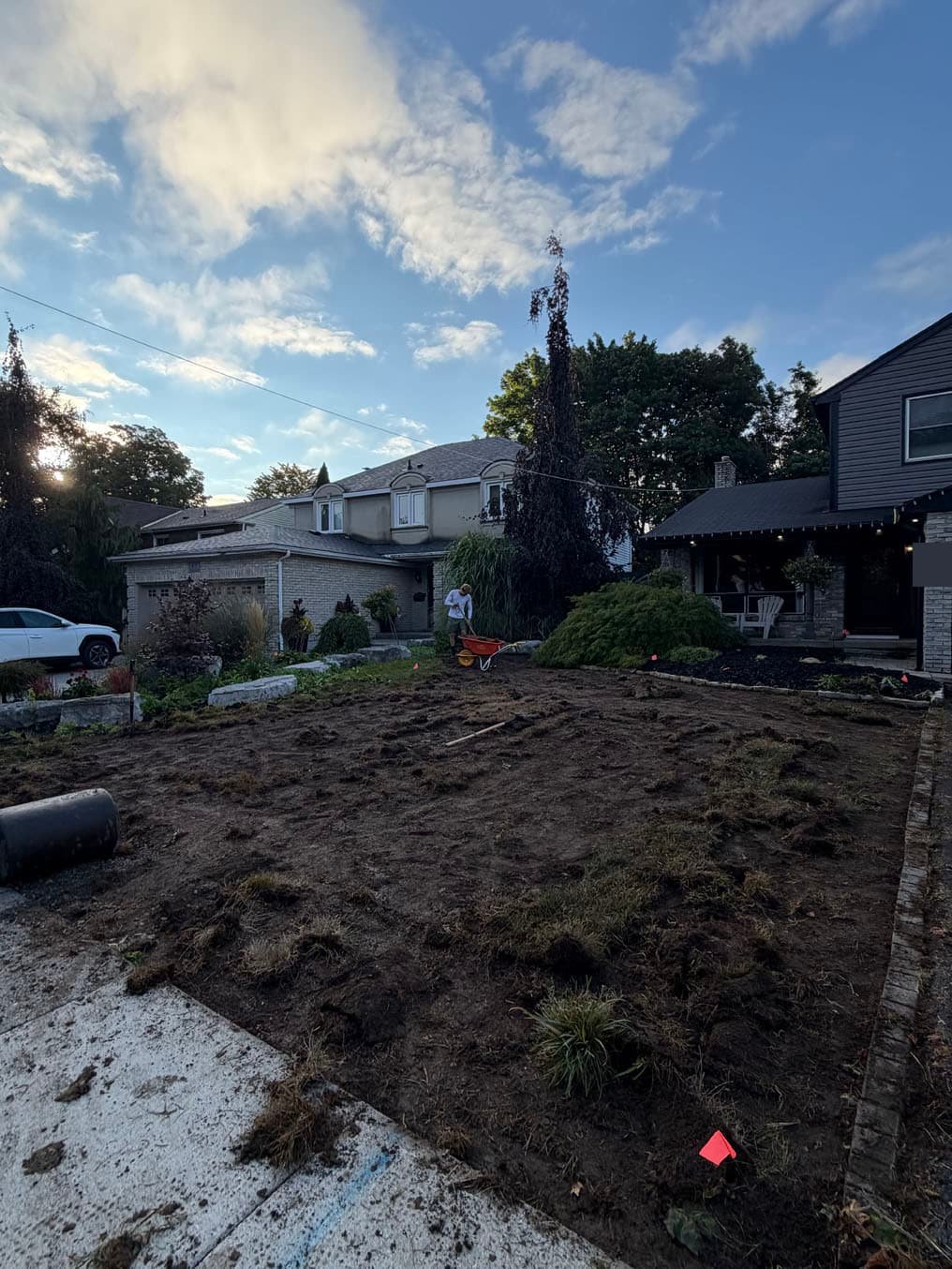 Bare, clumpy soil across the whole front lawn between the driveway and the sidewalk in Forest Heights, Kitchener, before grading and new sod