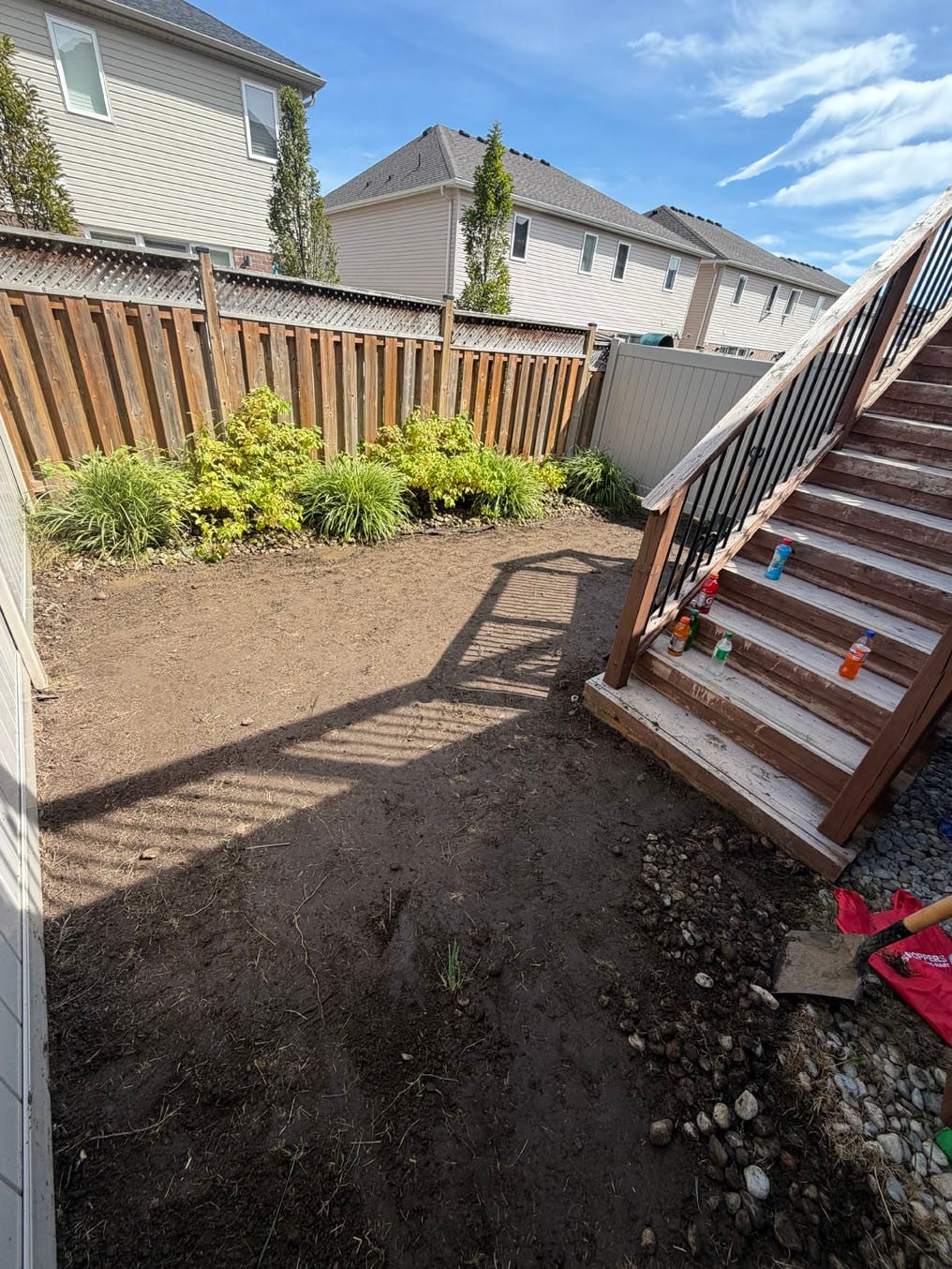 Fresh topsoil graded across a fenced back yard to the deck stairs at a Kitchener job