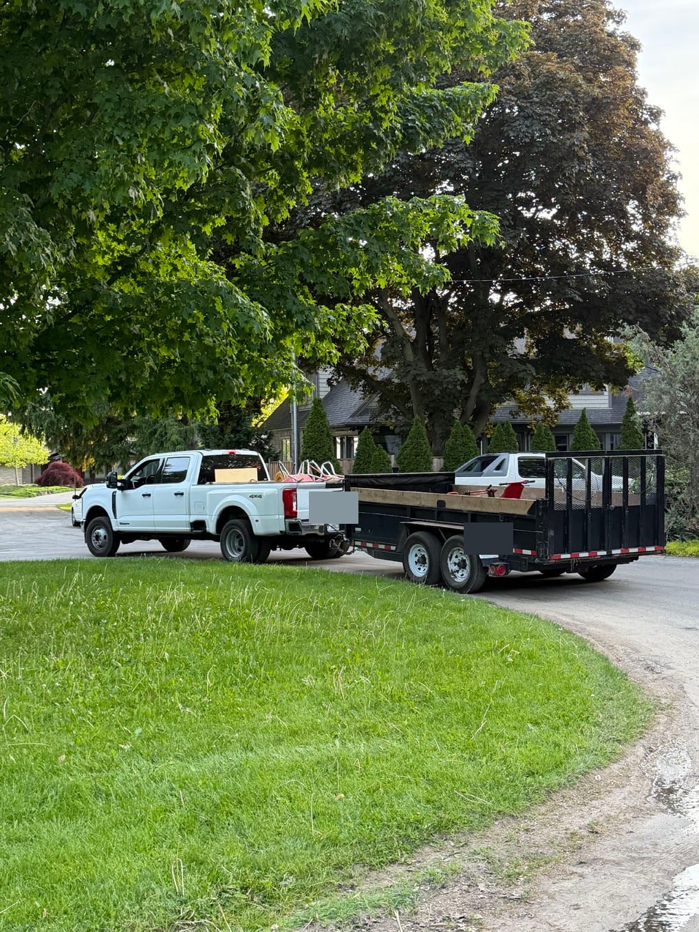 Crew truck and dump trailer at the curb with the old turf loaded, on a Kitchener front lawn