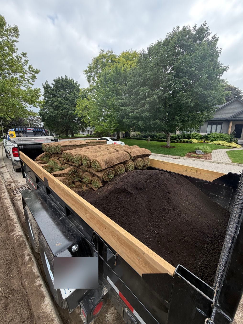 Sod Installation On Stanley Drive, Waterloo 9 Kentucky bluegrass sod rolls and topsoil arriving on a dump trailer at the curb on Stanley Drive, Waterloo