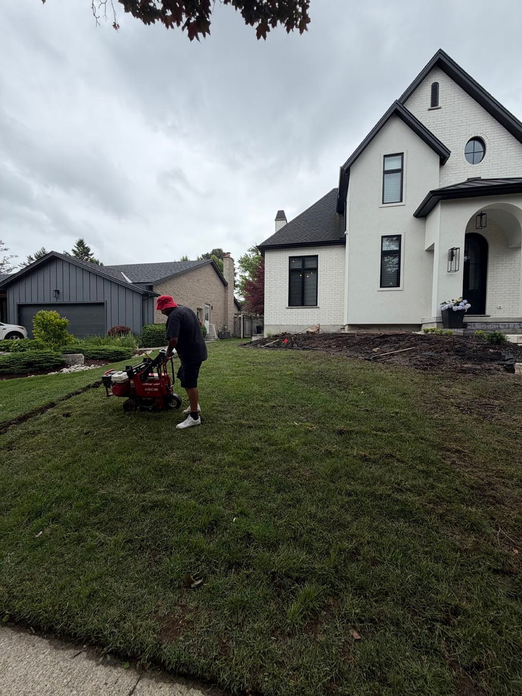 Front Lawn Sod Replacement In Westmount, Kitchener 1 Crew member running a sod cutter across the thin old front lawn at a white-brick home in Westmount, Kitchener