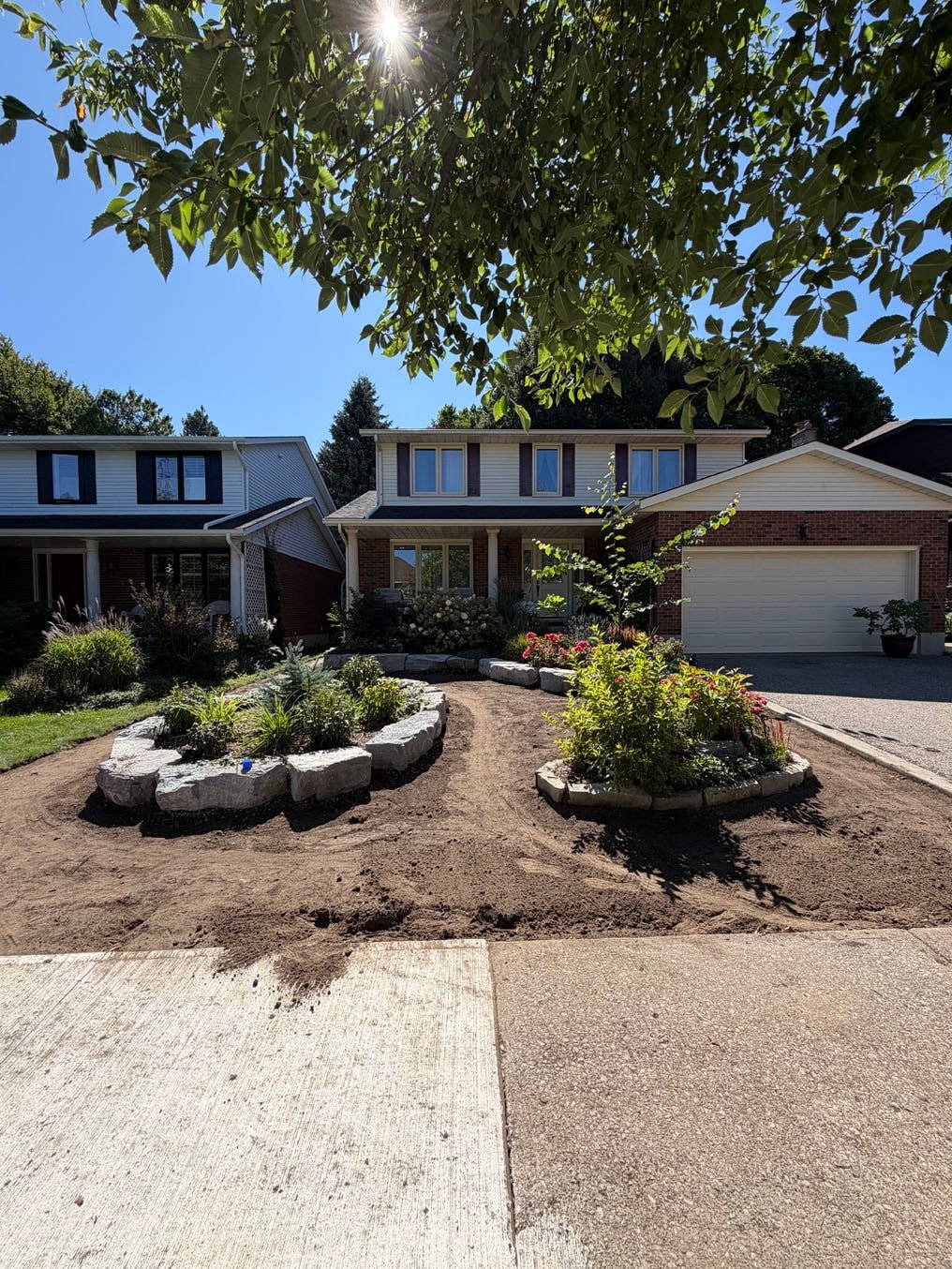 Front lawn on Woodbend Crescent, Waterloo, stripped and graded with fresh topsoil around two stone-edged garden beds, ready for sod